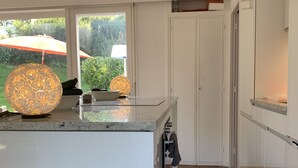 Une cuisine moderne dotée d’un grand îlot central, de meubles blancs et d’un sol en briques.