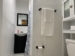 A bathroom with a white sink, a black cabinet, a white toilet, and a towel hanging on a black towel rack.