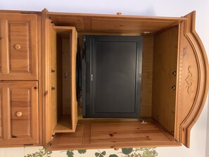 A wooden cabinet with a black door, a small shelf, and a drawer.