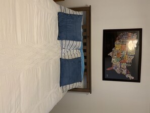 Restful retreat with a neatly made bed and a framed map nearby.