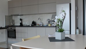 Una cucina moderna con mobili grigi, un tavolo da pranzo con sedie e una lampada a sospensione.