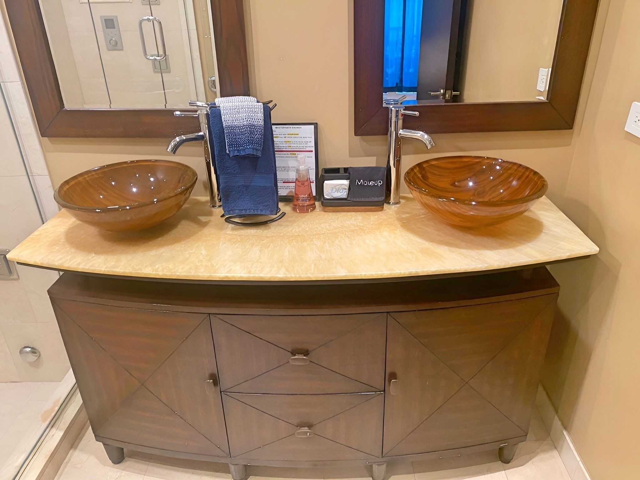 Un baño con tocador de doble lavabo, un espejo y un mueble con cajones.