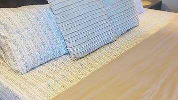 Una cama bien hecha con almohadas a rayas y una colcha estampada con motivos florales.