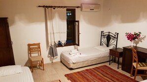 Ein Schlafzimmer mit Bett, Schreibtisch, Stuhl, Kleiderschrank und einem Fenster mit Vorhängen.