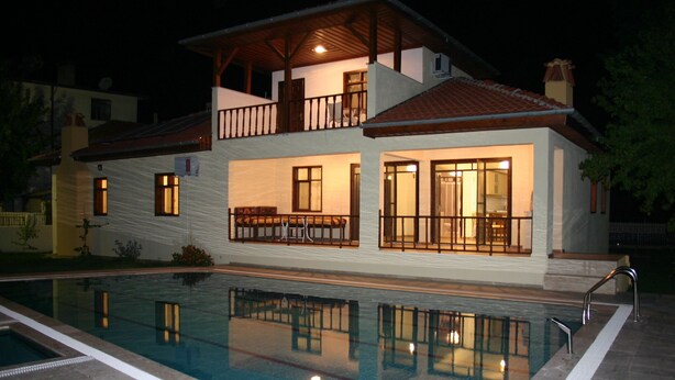 Ein zweistöckiges Haus mit Pool, Balkon und einem hellen Innenraum.