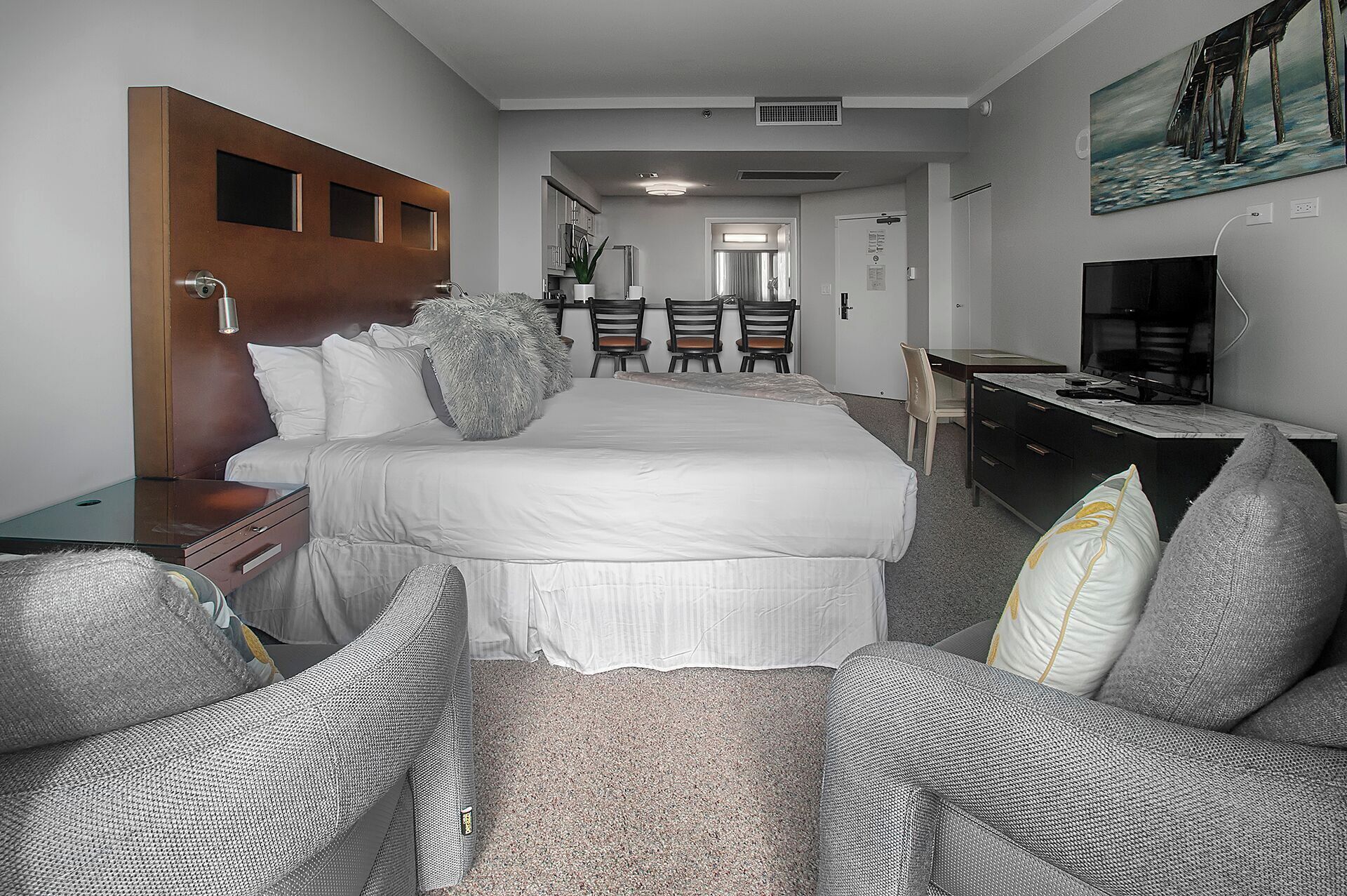A hotel room with a large bed, a desk, a chair, and a television.