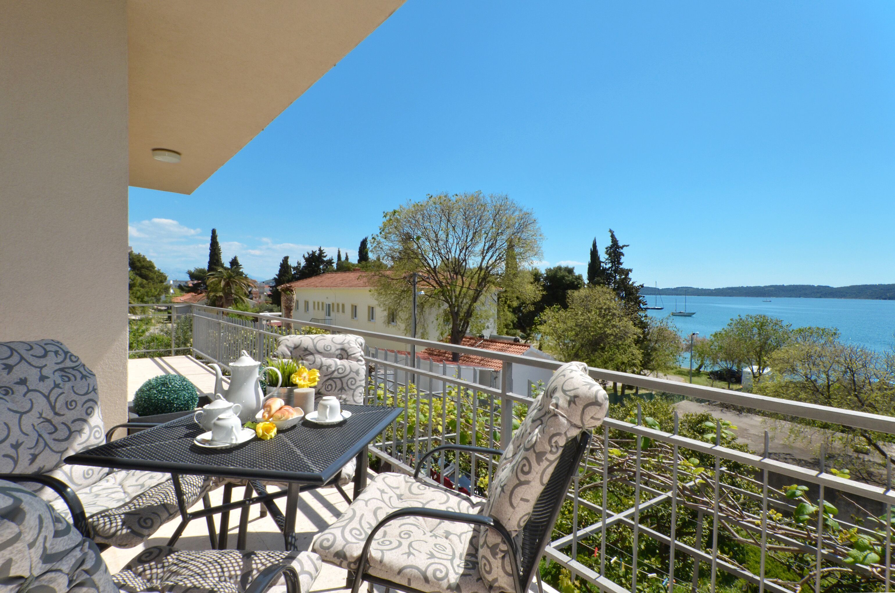A balcony with a table set for two, overlooking a body of water with boats.