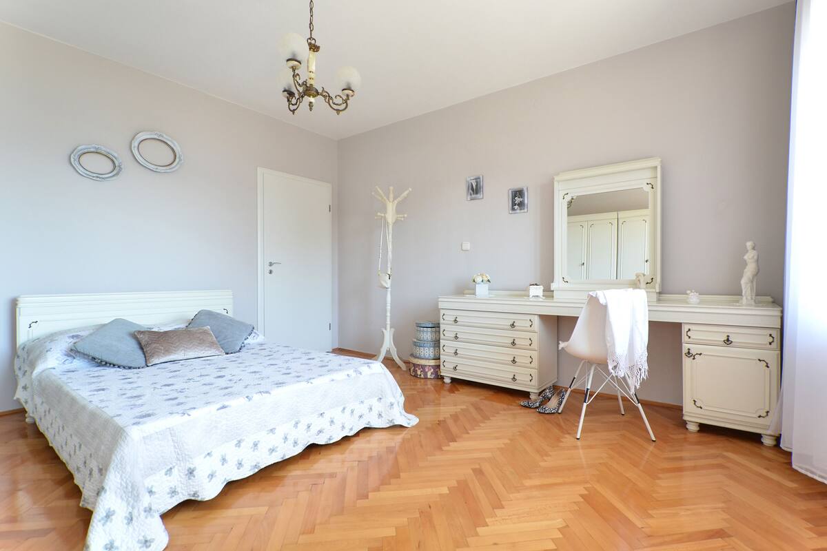 A bedroom with a bed, dresser, and a chair.