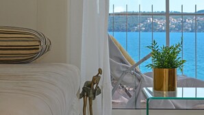 Una habitación con una cama, una planta en maceta y vista al mar.