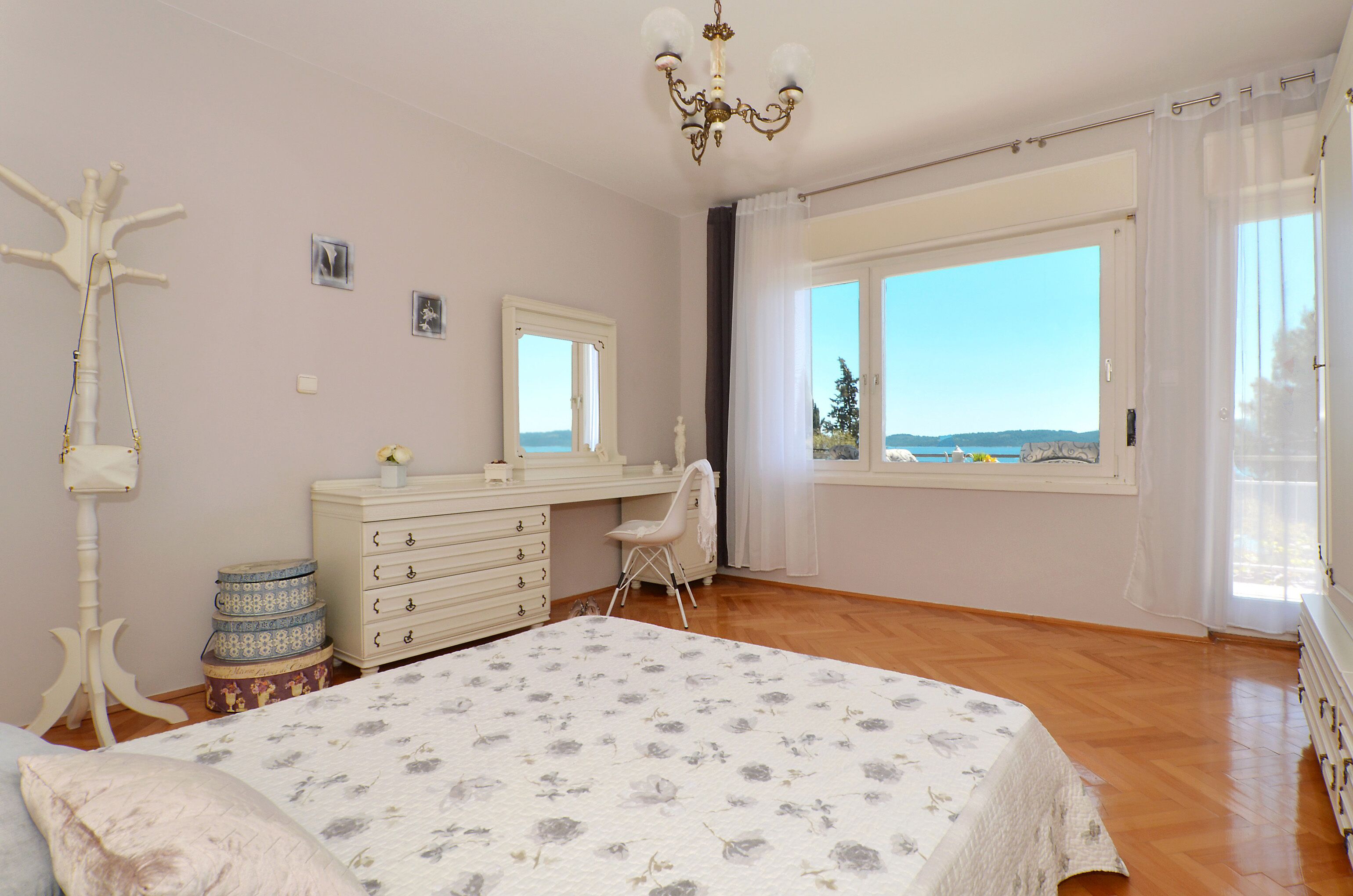 A bedroom with a large bed, a dresser, a chair, and a window with a view.