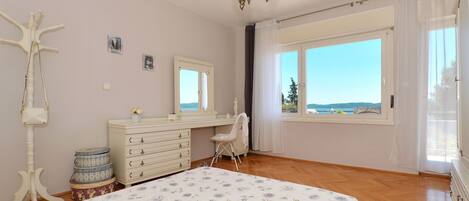 A bedroom with a large bed, a dresser, a chair, and a window with a view.
