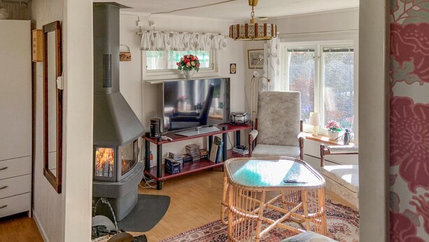 Ein gemütliches Wohnzimmer mit Kamin, Fernseher und bequemen Sesseln.