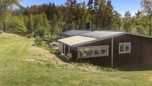 Eine eingeschossige Holzhütte mit geneigtem Dach, einer kleinen Veranda und einem Fenster.