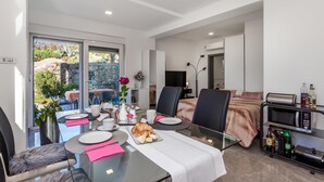 A modern hotel room with a dining area, a bed, and a kitchenette.