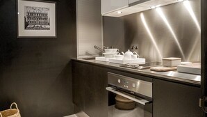 A modern kitchen with stainless steel appliances, a built-in oven, and a large window with blinds. - Cadogan Square - 1 bed (London)