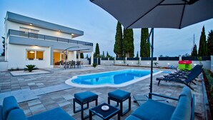 Una casa moderna con piscina, mobiliario exterior y zona de patio.