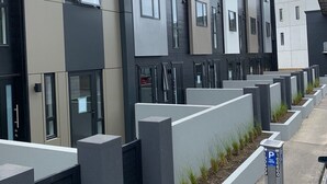 Un bâtiment moderne doté de plusieurs balcons et d’un espace de stationnement avec un panneau indicateur.