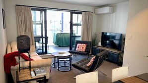 Un salon moderne avec un canapé, des fauteuils, une table basse et un téléviseur.