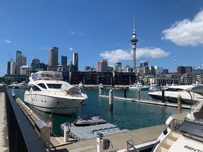A marina with yachts docked, a city skyline in the background, and a prominent tower.