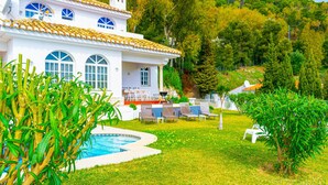 Una villa bianca con piscina, immersa nel verde e circondata da un paesaggio collinare.