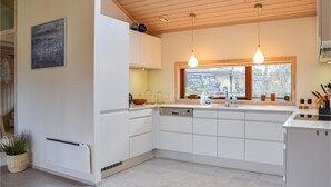 Ett modernt kök med vita skåp, en inbyggd diskmaskin och ett fönster med utsikt över omgivningen.