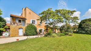 Une maison à deux étages avec une façade en pierre, un toit en tuiles et une pelouse bien entretenue.