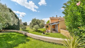 Une maison dotée d’un patio, entourée d’une végétation luxuriante et d’arbres.