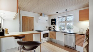A modern kitchen with wooden flooring, a central island, a stove, and a dishwasher. - 3 bedroom awesome home in Ringkøbing (Lem St)