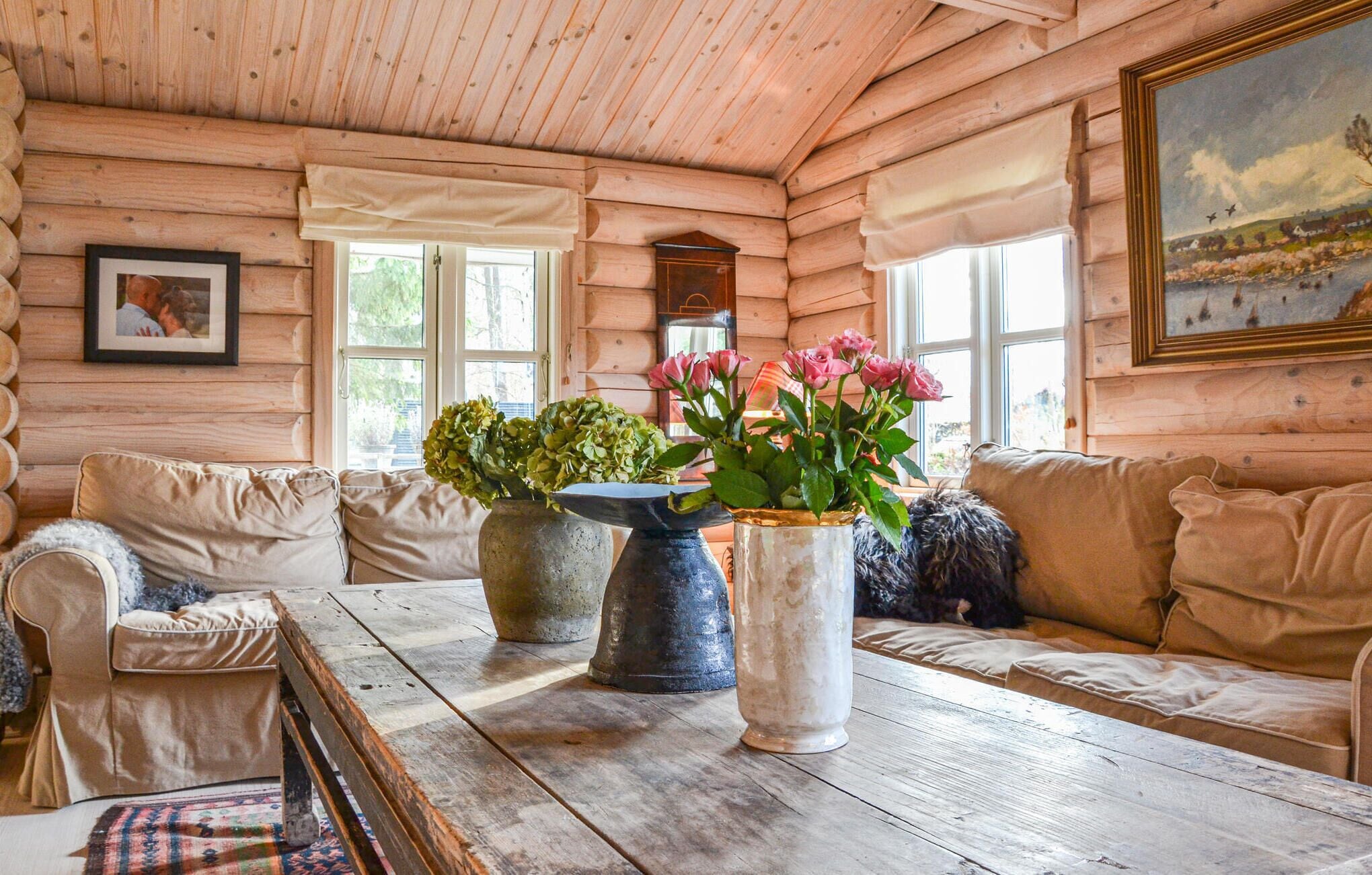 L’intérieur d’un chalet confortable, avec des murs en bois, une table en bois, deux canapés et de grandes fenêtres.