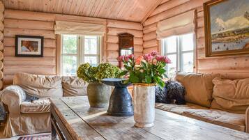 L’intérieur d’un chalet confortable, avec des murs en bois, une table en bois, deux canapés et de grandes fenêtres.