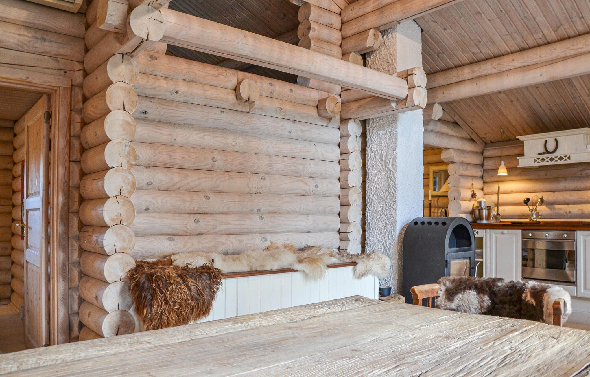 A log cabin interior with a rustic wooden interior, a fireplace, and a kitchen area.