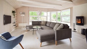Ein modernes Wohnzimmer mit einer Eckcouch, einem runden Couchtisch und einem an der Wand befestigten Fernseher.
