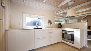 Eine moderne Küche mit weißen Schränken, einem eingebauten Backofen und einem Fenster mit Blick auf eine verschneite Landschaft.