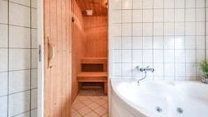 Ein Holzinnenraum mit einer Badewanne und gefliesten Wänden.