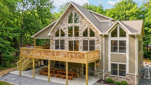 A two-story stone house with a balcony and outdoor seating area. - Rainier by PMR, 8BR, Elevator, Outdoor Fireplace, Double Kitchen, Sleeps 26 (Lake Harmony)