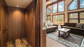 A wooden elevator and a living area with a sofa, coffee table, and large windows. - Rainier by PMR, 8BR, Elevator, Outdoor Fireplace, Double Kitchen, Sleeps 26 (Lake Harmony)