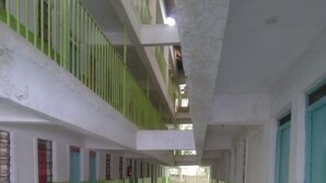 A long, narrow corridor with green and white walls, tiled floors, and multiple doors along the sides. - Green Court Hotel (Bondo)