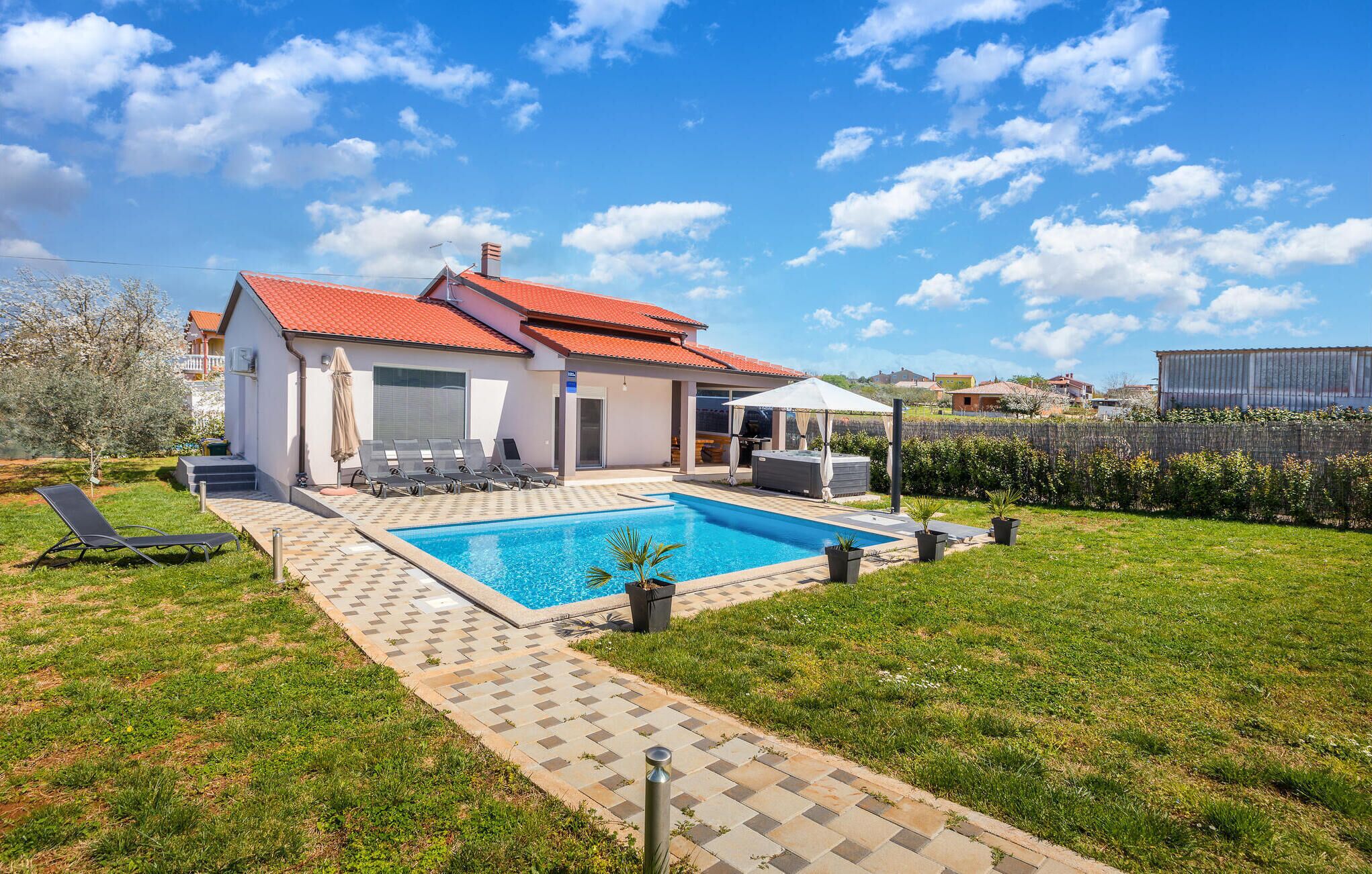 A modern house with a swimming pool, outdoor seating, and a well-maintained garden.