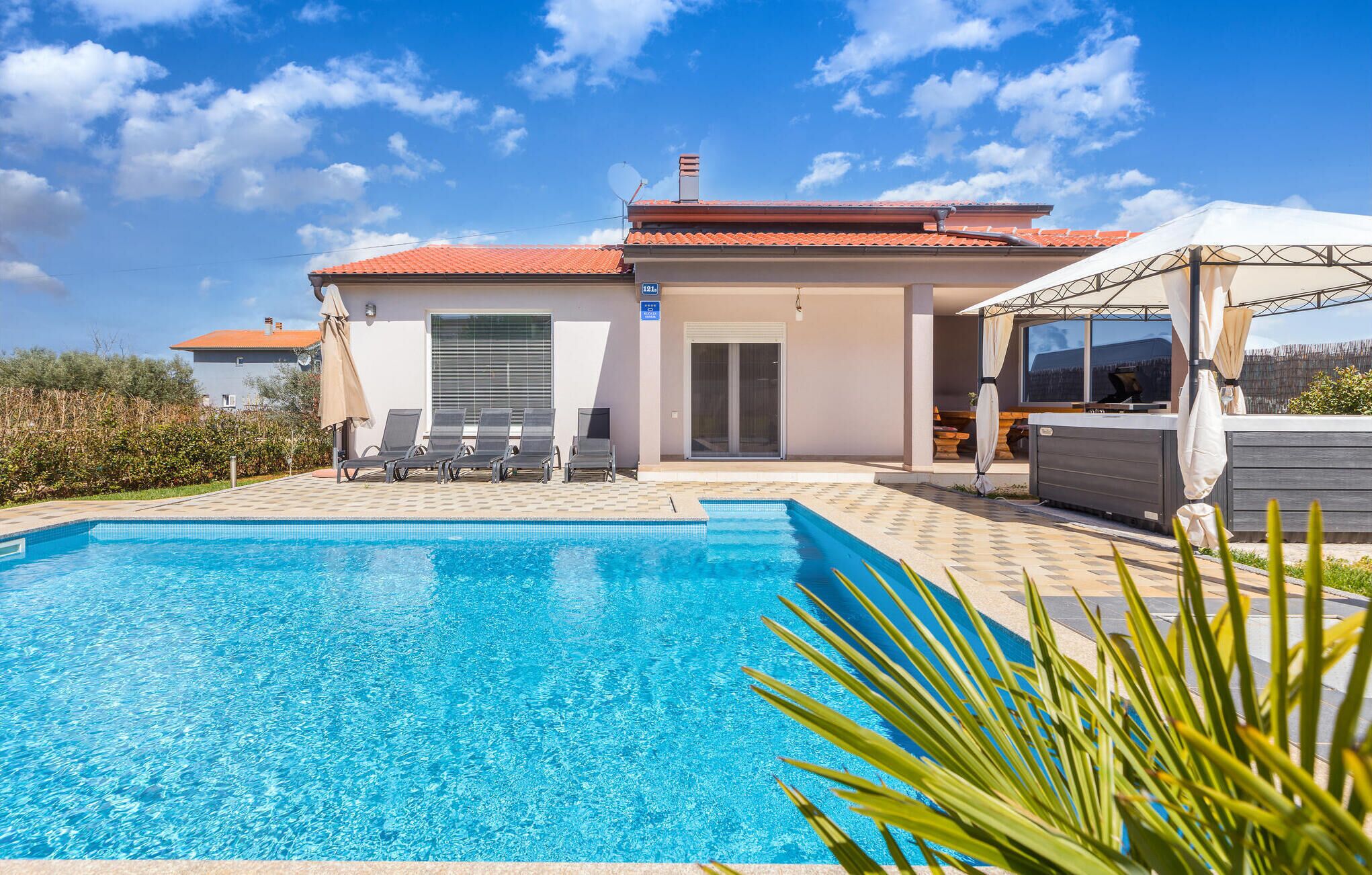 En modern villa med pool, utomhusmöbler och ett område för grillning.