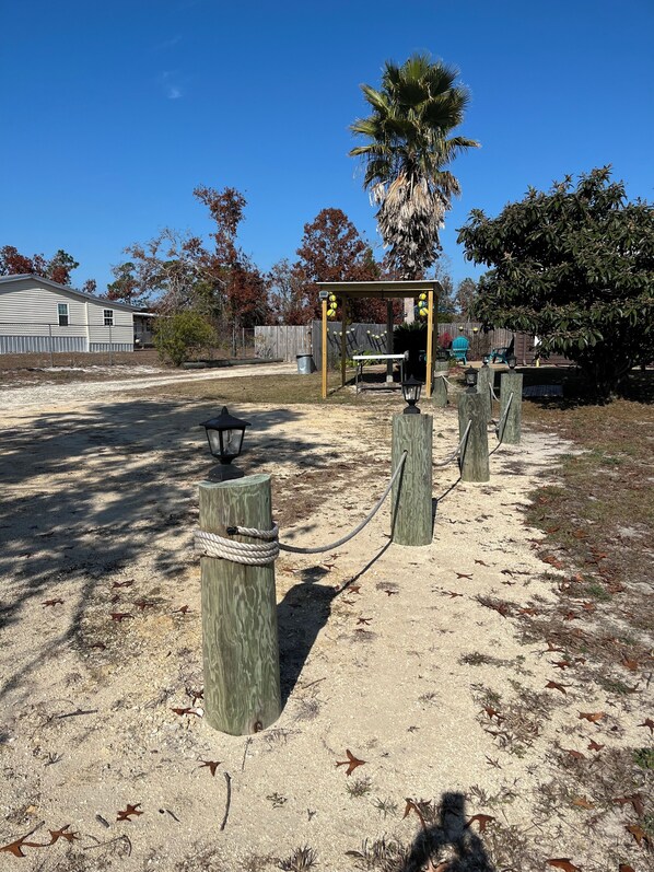 A fenced outdoor area with a wooden structure, possibly a gazebo, and a palm tree.