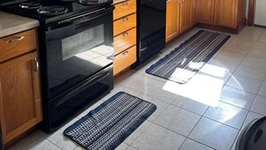 Une cuisine avec des meubles en bois, une cuisinière noire, un lave-vaisselle et un four à micro-ondes.