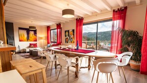 Un comedor con una mesa redonda, sillas blancas y cortinas rojas.