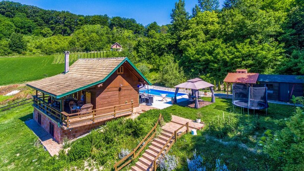 Une cabane en bois avec une piscine, un espace salon extérieur et un trampoline.