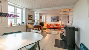 Ein gemütliches Wohnzimmer mit Essbereich, Kamin und einer Treppe, die zu einer oberen Ebene führt.