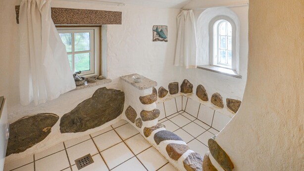 A rustic bathroom with stone walls, a window, and a bathtub.