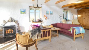 A cozy living room with a stone fireplace, wooden furniture, and a large wooden cabinet.