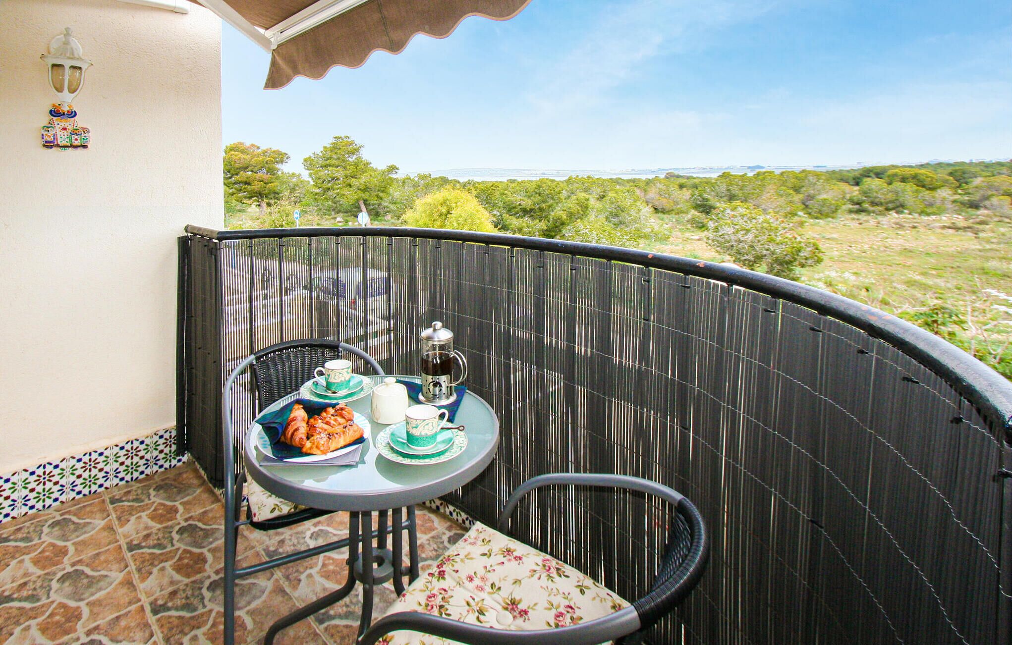 Ein kleiner Balkon mit Tisch für zwei Personen, ausgestattet mit Teekanne, Tassen und Gebäck.