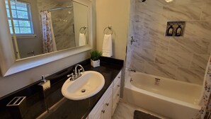 Een moderne badkamer met een grote spiegel, een wastafel, een badkuip en een douche.