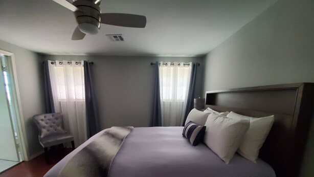 Een hotelkamer met een groot bed, een plafondventilator en een stoel.