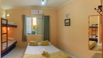 A bedroom with a bunk bed, a single bed, a window with curtains, a ceiling fan, and a wall-mounted air conditioner.